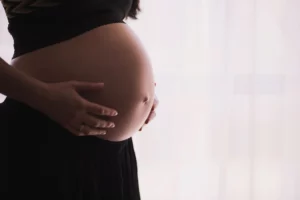 Mulher gestante segura a barriga para representar a diabetes gestacional.