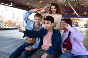 Dois meninos e duas meninas tiram selfie em um smartphone. Os jovens representam a puberdade.